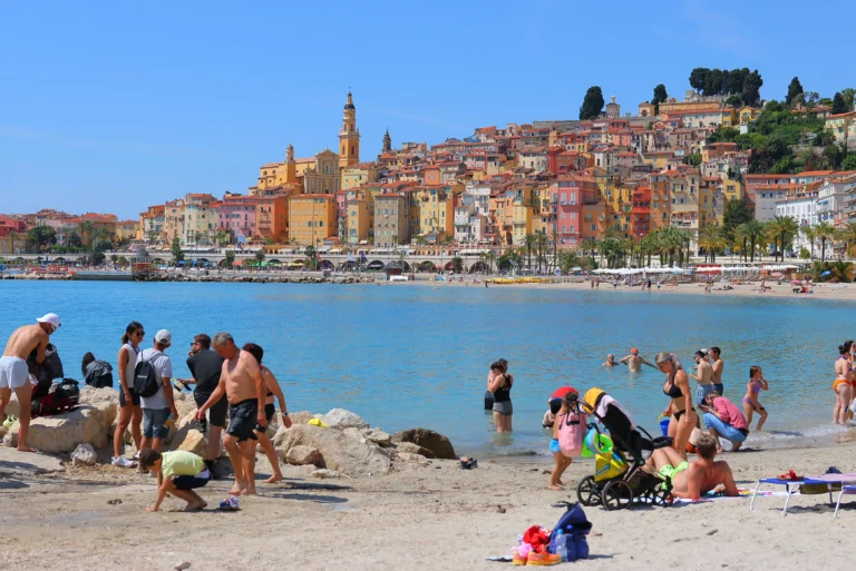 Photo de la plage team village avec des baigneurs et la ville de Menton en arrière plan